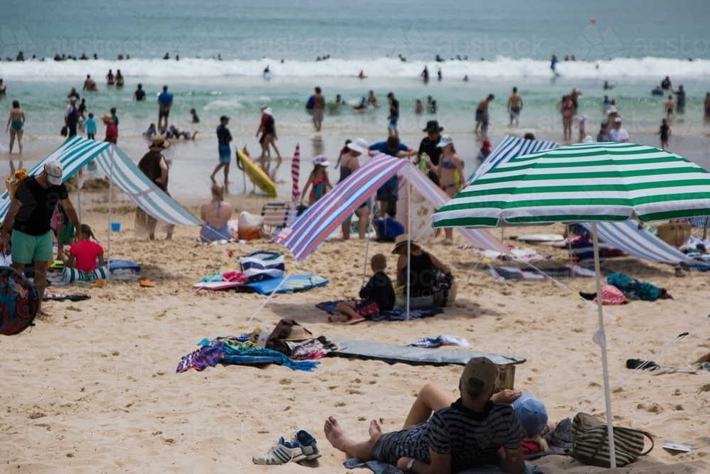 People relaxing under beach umbrellas at noosa main beach in summer - Australian Stock Image