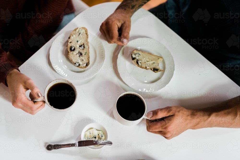 People sitting at a table drinking coffee and eating artisan bread - Australian Stock Image