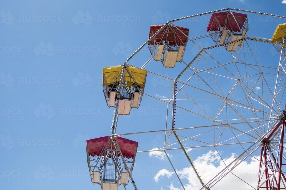 People sitting in carriage of ferris wheel up in air - Australian Stock Image