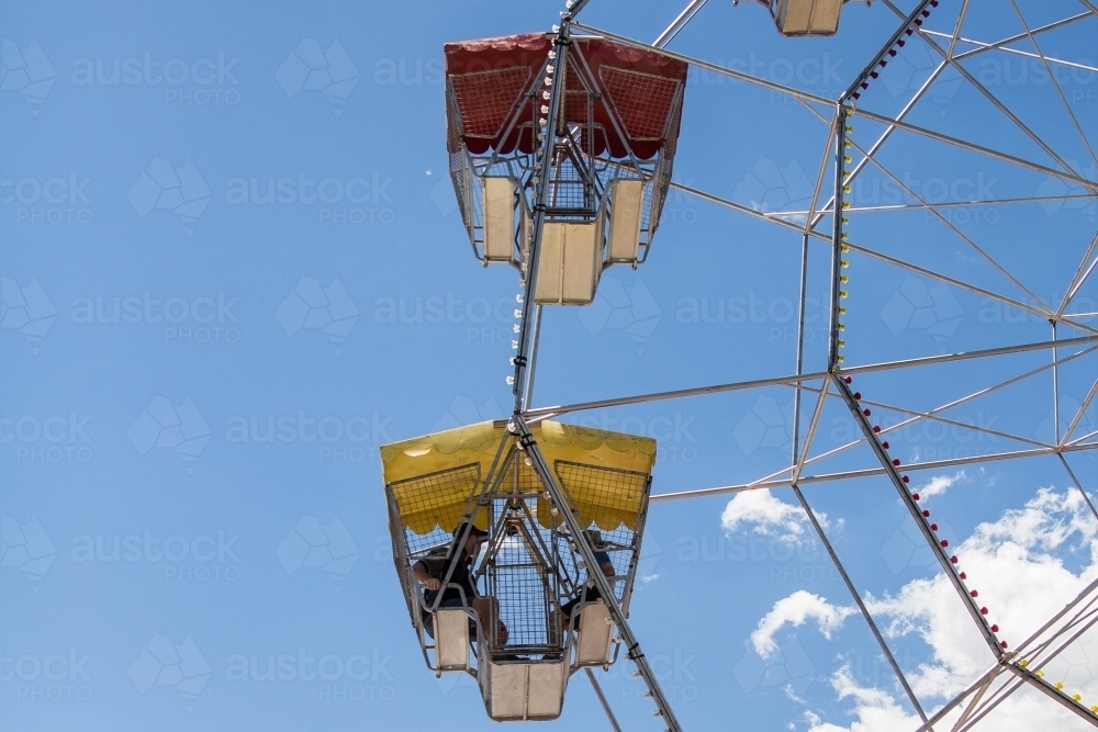 People sitting in carriage of ferris wheel up in air - Australian Stock Image