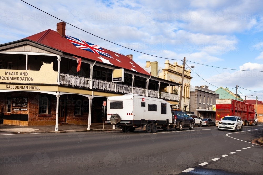 People travelling down highway through country town with caravan - Australian Stock Image