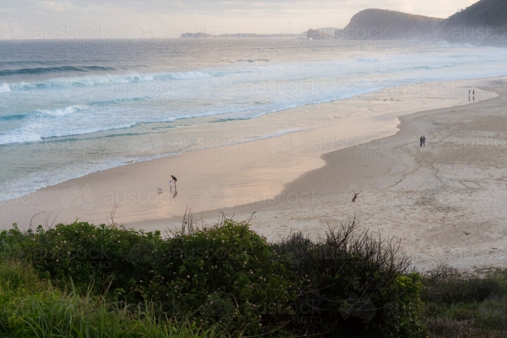 People walking along blueys beach at sunset - Australian Stock Image