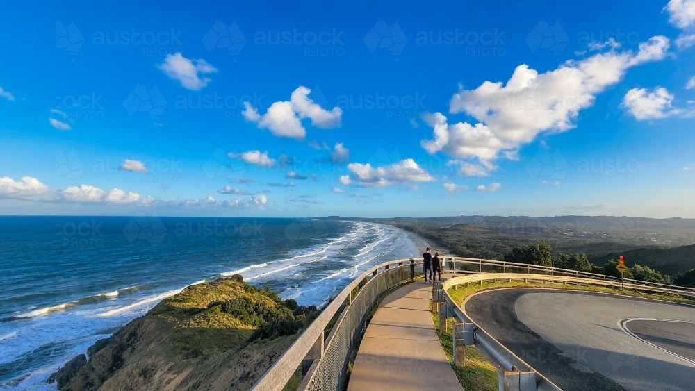 People walking along path at Cape Byron with view over Tallow Beach at Byron Bay - Australian Stock Image