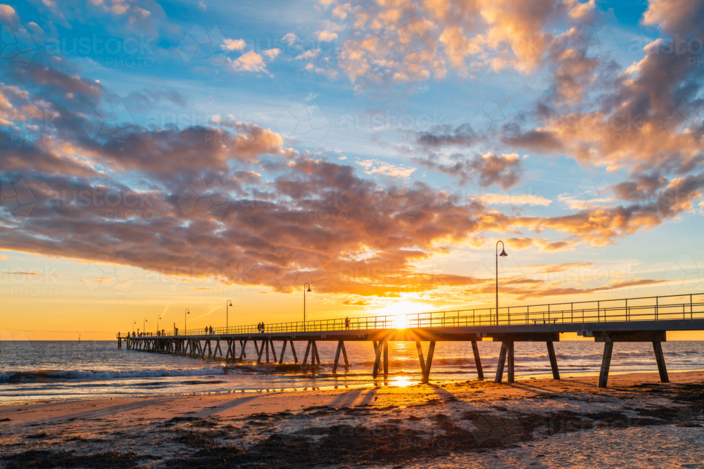 People walking on Glenelg Beach jetty during beautiful sunset, South Australia - Australian Stock Image