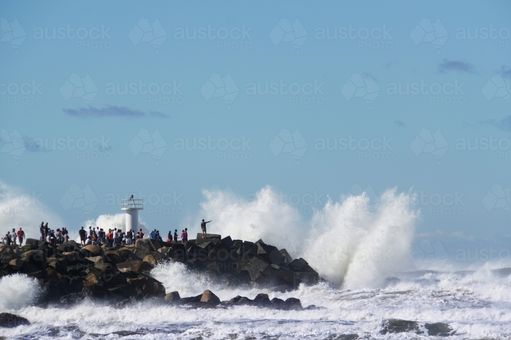 People watching waves crashing on rocks - Australian Stock Image