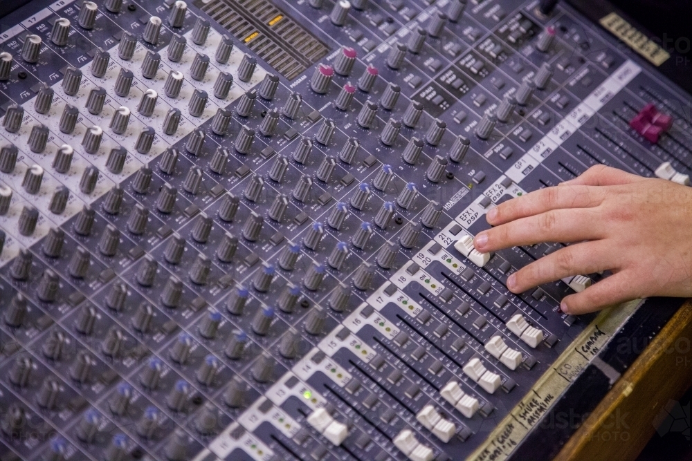 Person adjusting knobs on a sound system - Australian Stock Image