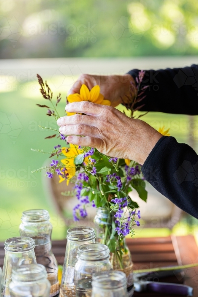 Person making flower arrangement for wedding with sunflower and geisha girl flower (Duranta erecta) - Australian Stock Image