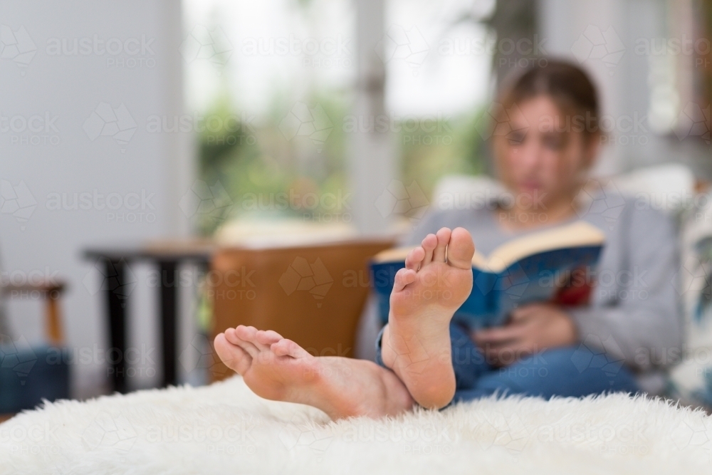 Person reading with feet up on footstool - Australian Stock Image