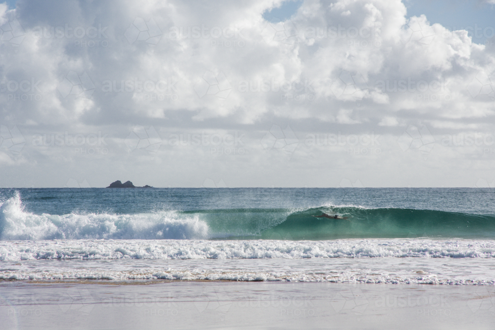 Person swimming in wave breaking at Byron Bay - Australian Stock Image