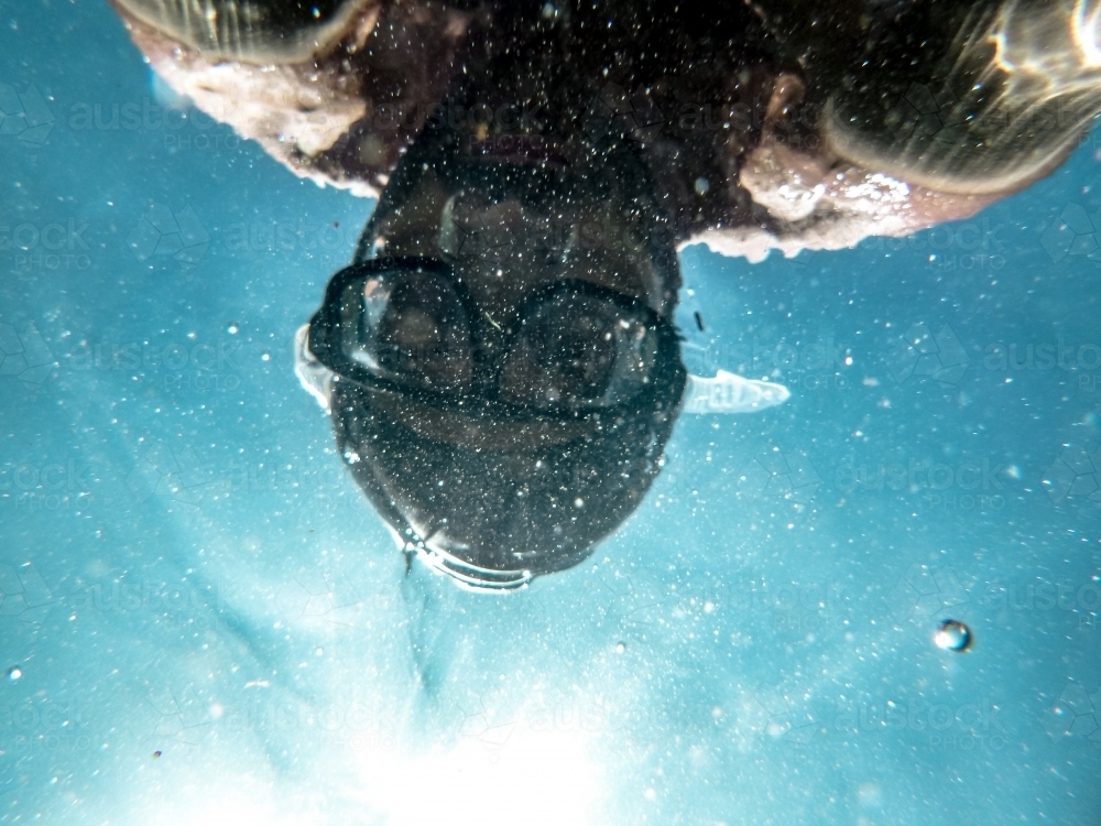 person swimming underwater wearing diving mask on a sunny day - Australian Stock Image