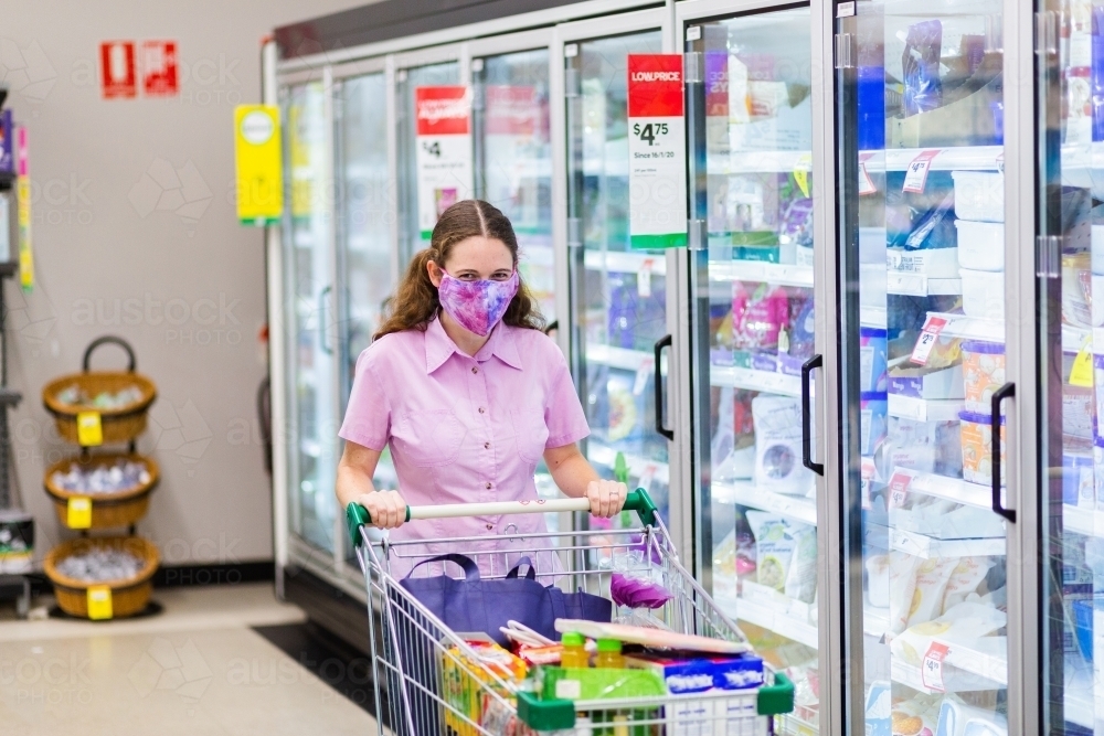 person walking down grocery store aisle wearing a home made face mask during covid-19 pandemic - Australian Stock Image