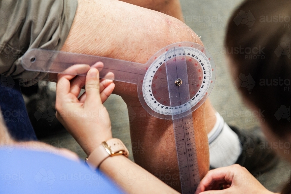 Physio measuring knee bend angle - Australian Stock Image