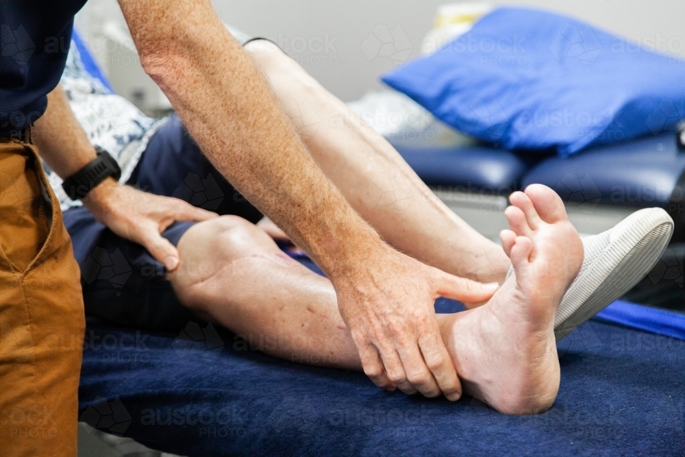 Physiotherapist working to rehabilitate client with leg injury - Australian Stock Image