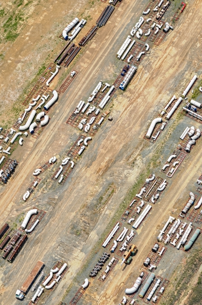 Pipes and industrial construction parts stocked on the ground for a liquefied natural gas plant - Australian Stock Image