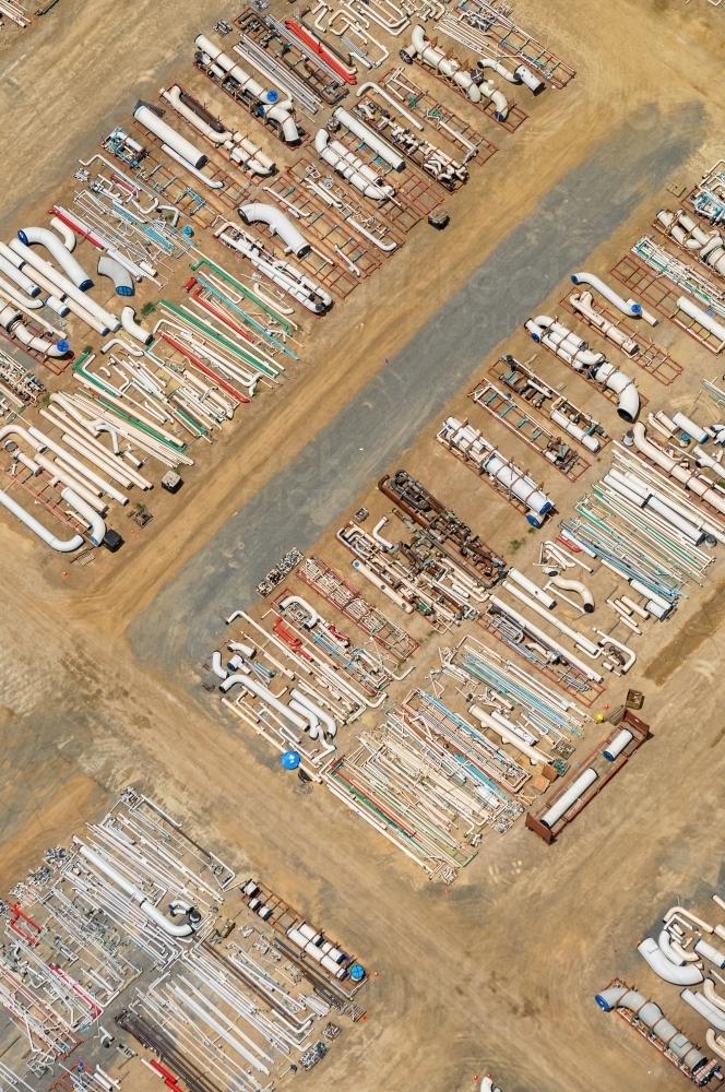 Pipes and industrial construction parts stocked on the ground for a liquefied natural gas plant. - Australian Stock Image