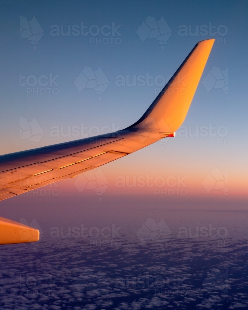 Plane wing over clouds at sunset - Australian Stock Image