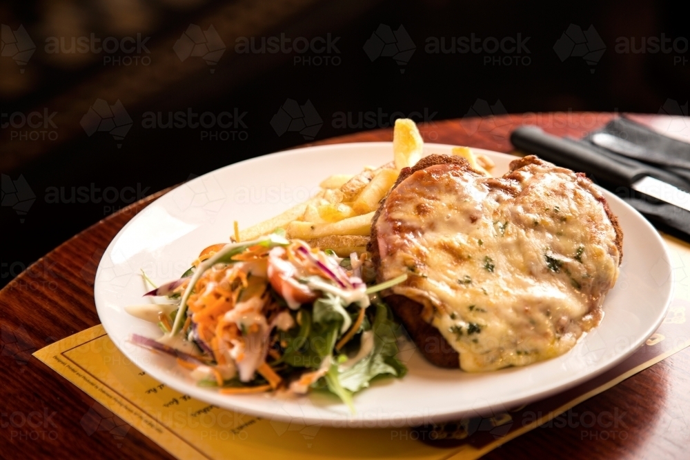 Plate of chicken parmigiana, salad and chips - Australian Stock Image