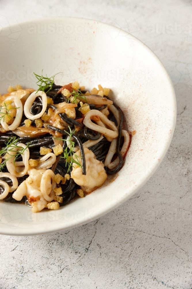 Plate of seafood and squid ink noodles - Australian Stock Image