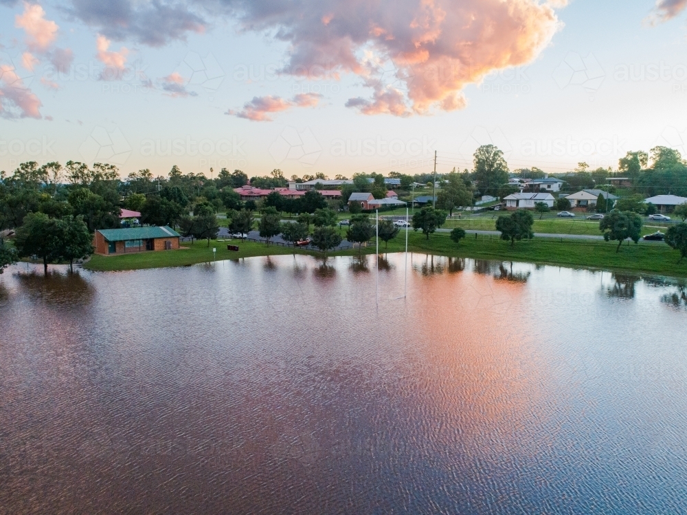 Playing field turned into a peaceful dam with sunset reflections during flood and river backflow - Australian Stock Image