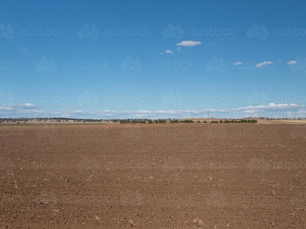 Ploughed paddock with brown soil and blue sky - Australian Stock Image