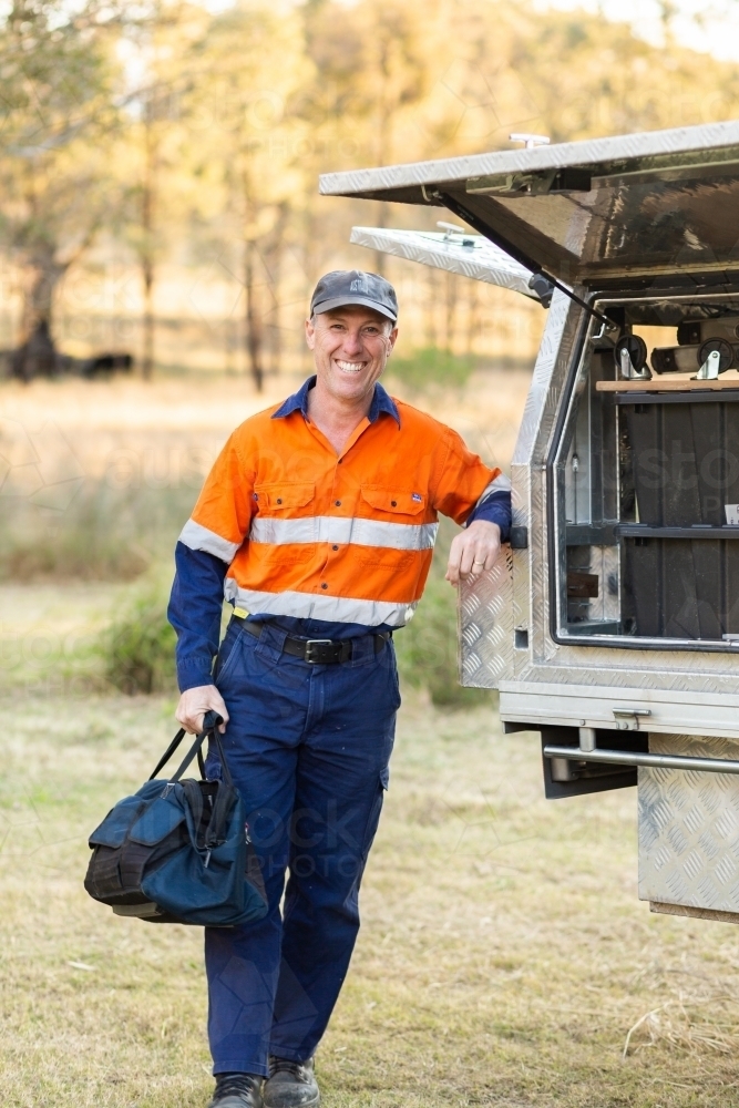 plumber tradie leaning on back of work ute - Australian Stock Image