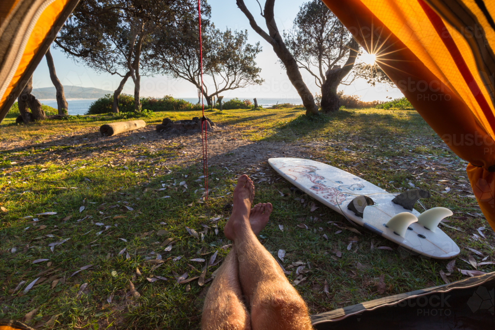 Point of view from a tent of man relaxing during crisp morning on a surf hike in Australia - Australian Stock Image