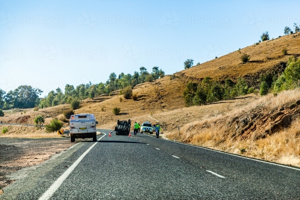 Police attending to car crash with flipped car on rural road - Australian Stock Image