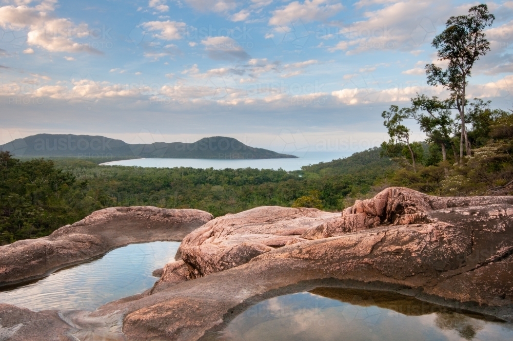 Pools in granite above Zoe Falls with views of Hinchinbrook Island in the background - Australian Stock Image