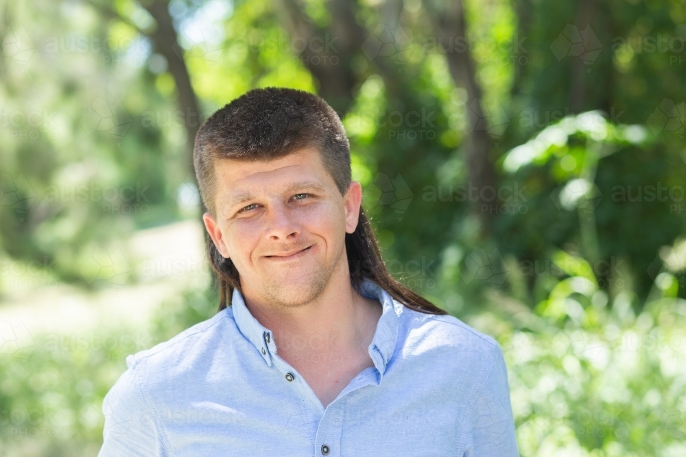 Portrait of a man outside with a mullet hairstyle in a button up - Australian Stock Image
