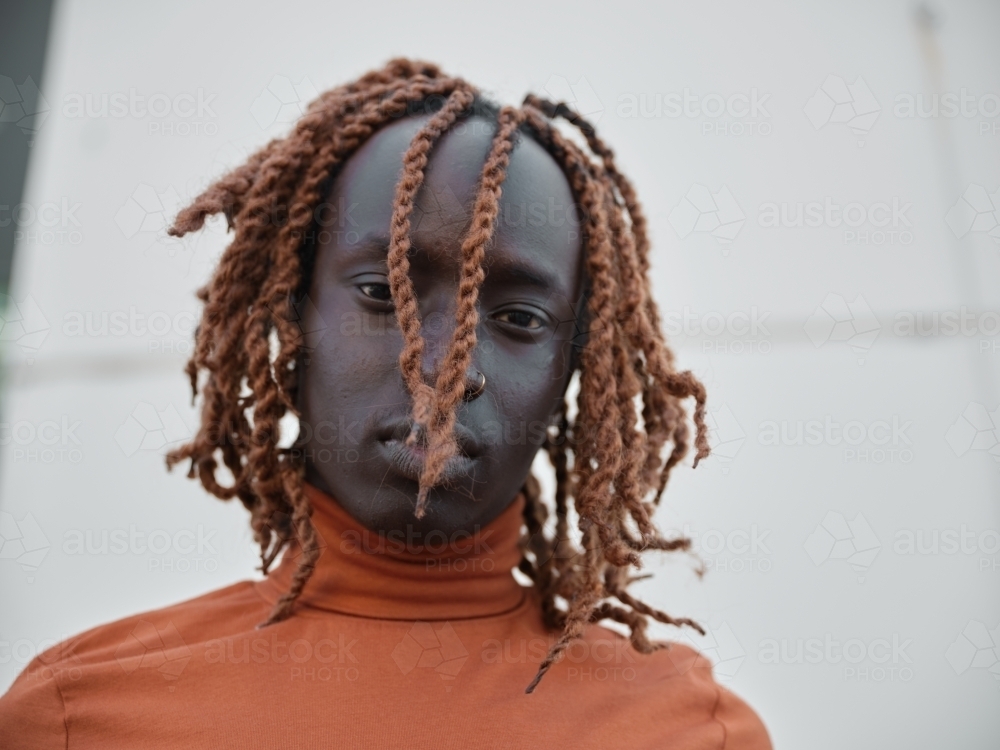 Portrait of a South Sudanese man wearing orange turtleneck - Australian Stock Image