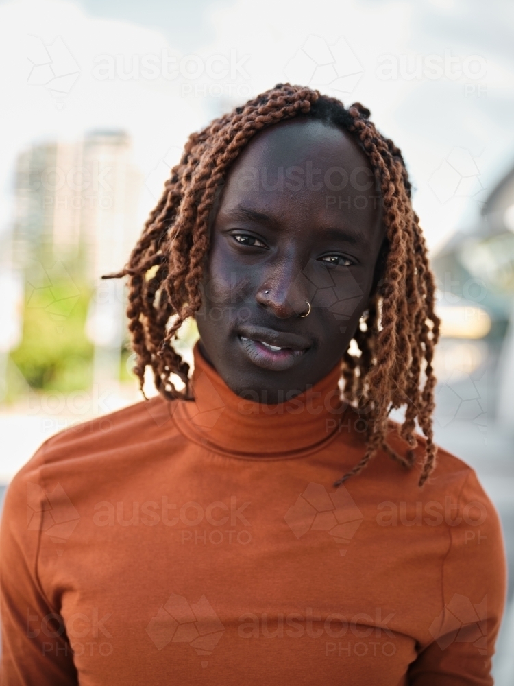 Portrait of a South Sudanese man wearing orange turtleneck - Australian Stock Image