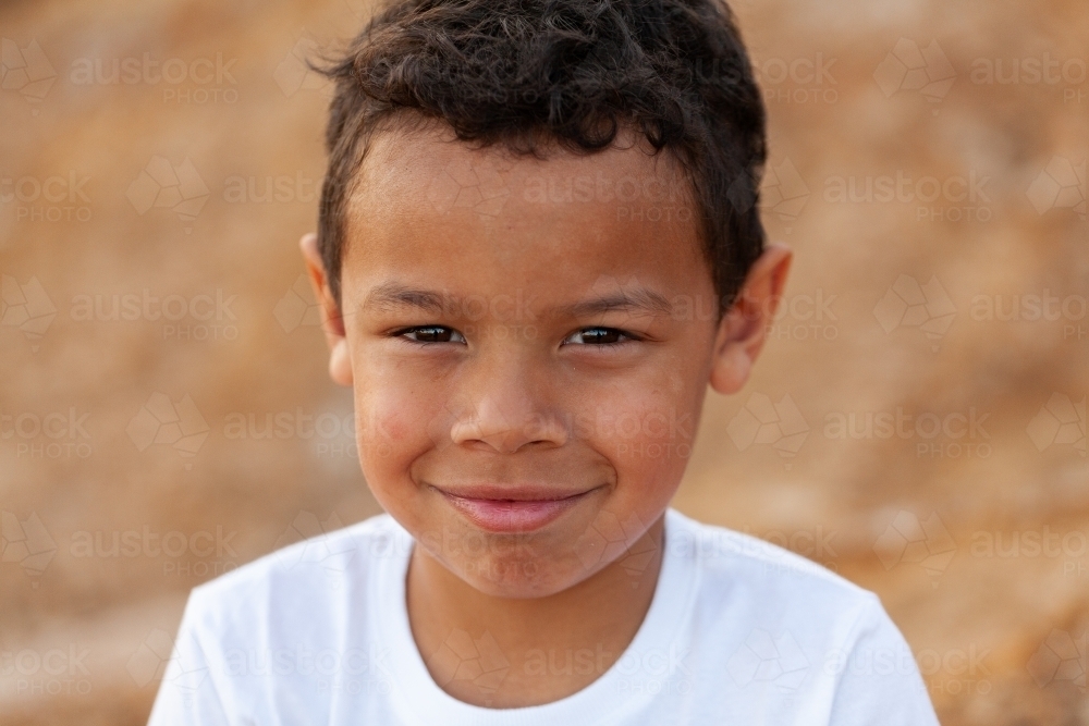 Portrait of a young aboriginal child against brown australian earth - Australian Stock Image