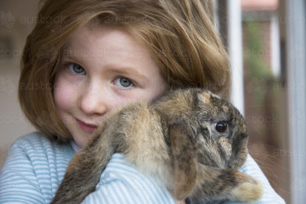 Portrait of a young girl cuddling a lop rabbit - Australian Stock Image