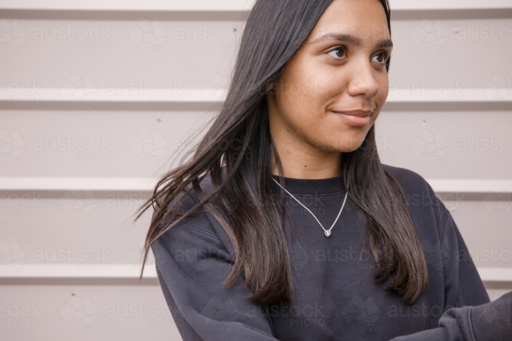 Portrait of a young, smiling,  first nations woman against wall outside - Australian Stock Image