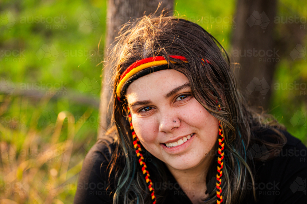 Portrait of Aboriginal Australian teenaged girl in golden light in bushland wearing headband - Australian Stock Image