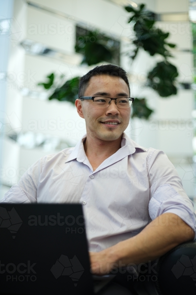 Portrait of Asian businessman on laptop in a workplace - Australian Stock Image