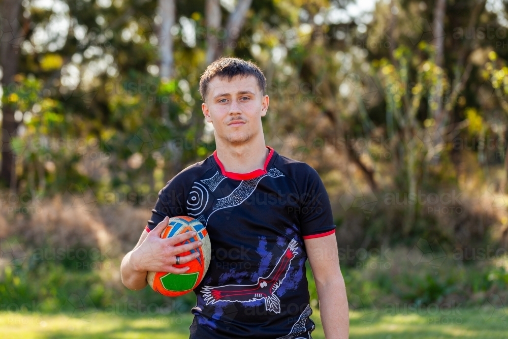 Portrait of Aussie teenager with footy game ball tucked under arm - Australian Stock Image