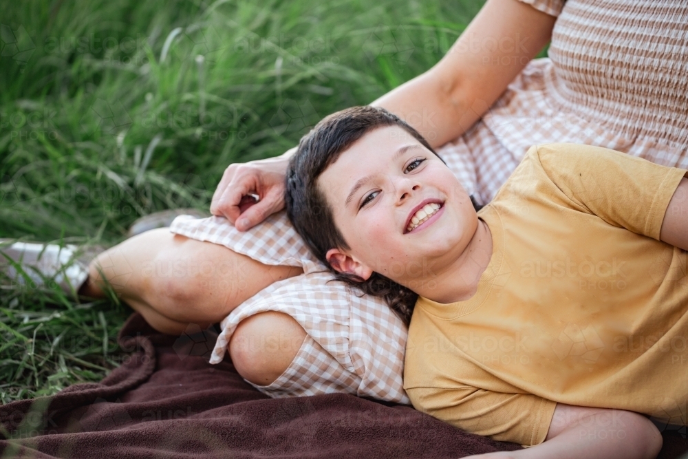 Portrait of boy lying on mother's lap in rural country bush setting - Australian Stock Image