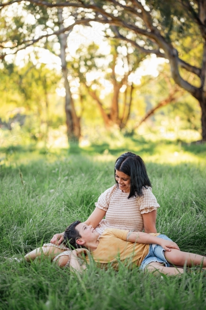 Portrait of boy lying on mothers lap in rural country bush setting - Australian Stock Image