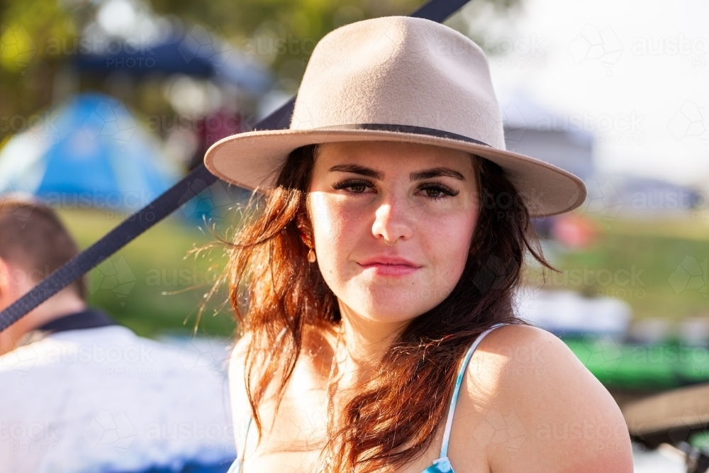 Portrait of brunette young lady relaxing outside by a lake with friends - Australian Stock Image