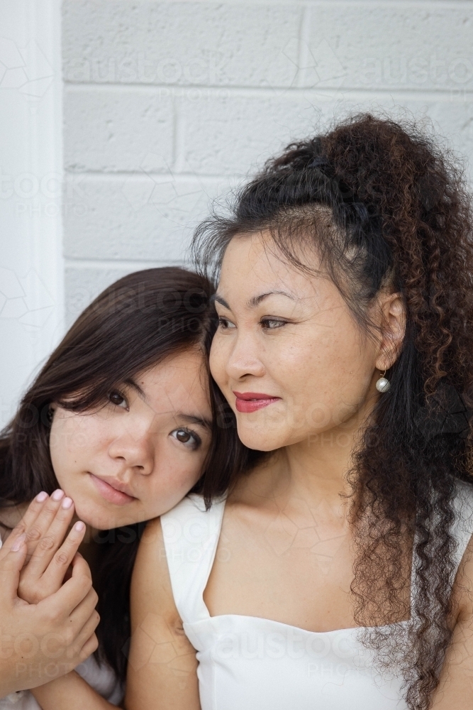 Portrait of daughter and mother against blank wall - Australian Stock Image