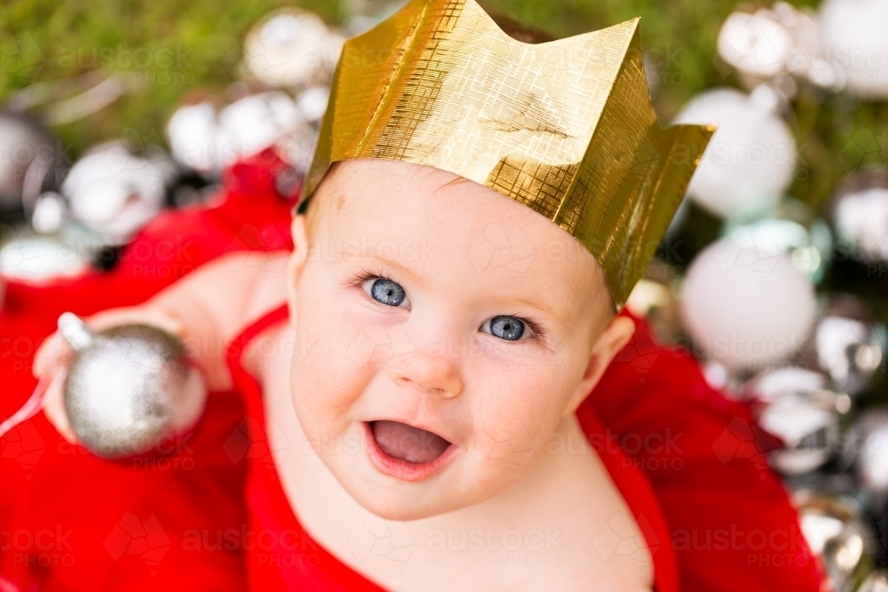 portrait of eight month old baby wearing Christmas paper crown hat - Australian Stock Image