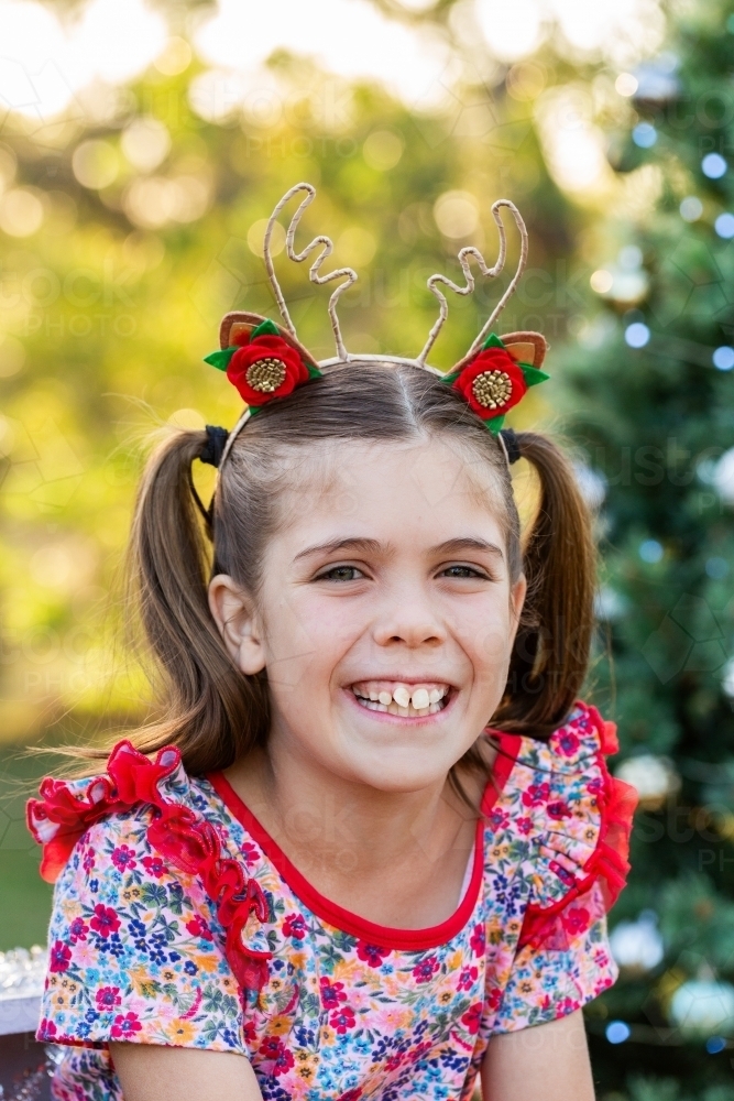 Portrait of grinning little girl with reindeer antlers for christmas - Australian Stock Image