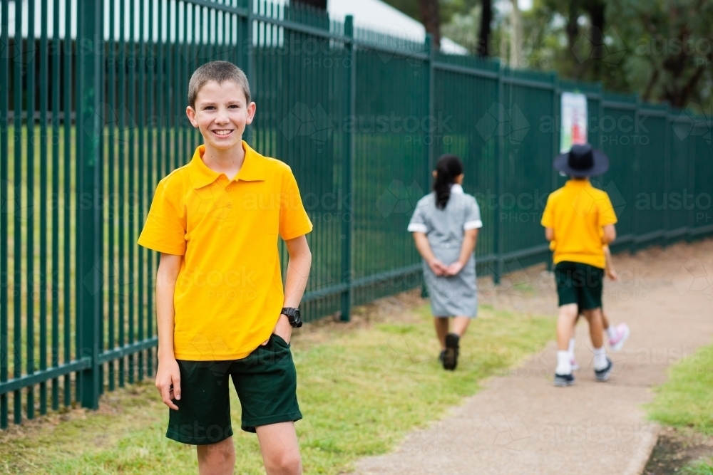 Portrait of happy Aussie school boy near school fence - Australian Stock Image