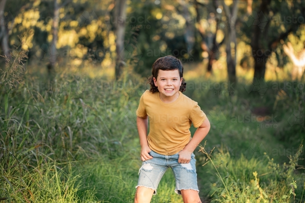 Portrait of happy boy wearing yellow shirt in Australian country bush setting - Australian Stock Image