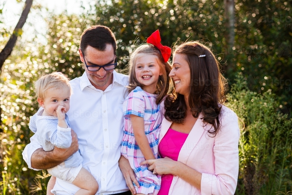 Portrait of happy family of four with two children and parents in late twenties - Australian Stock Image