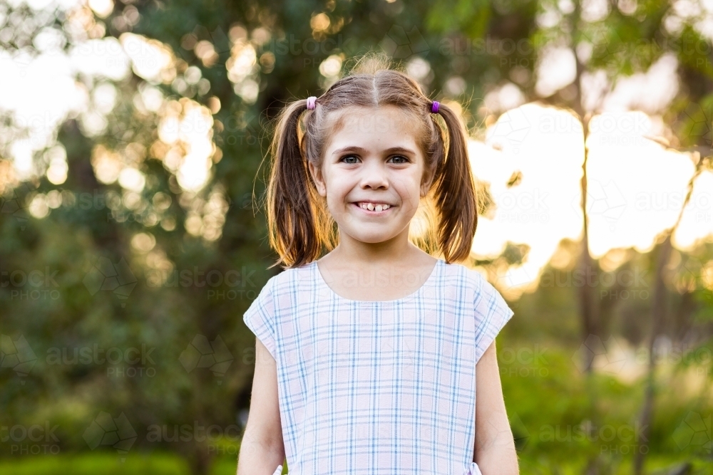Portrait of happy little eight year old girl with pigtails in country afternoon - Australian Stock Image