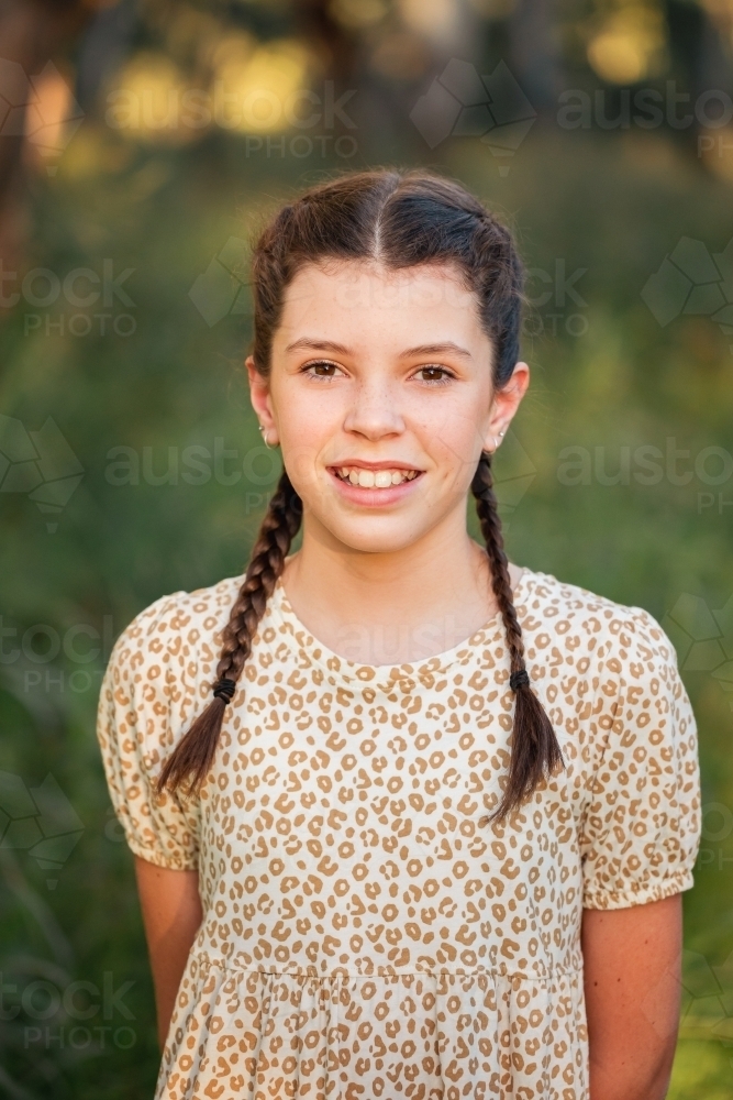 Portrait of happy pre-teen girl wearing dress in Australian country bush setting - Australian Stock Image