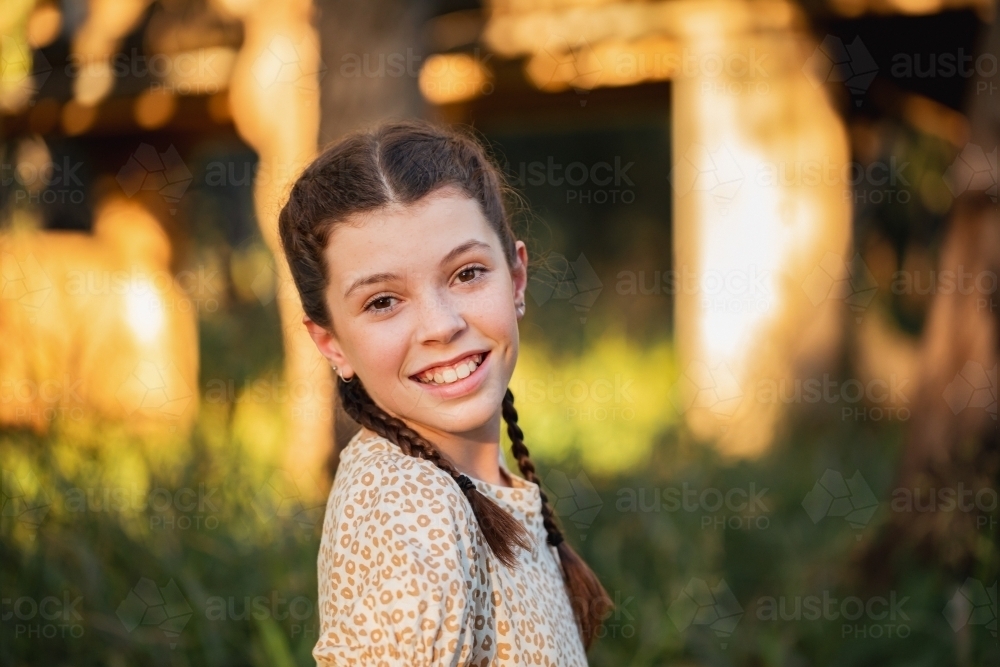 Portrait of happy pre-teen girl wearing dress in Australian country bush setting - Australian Stock Image