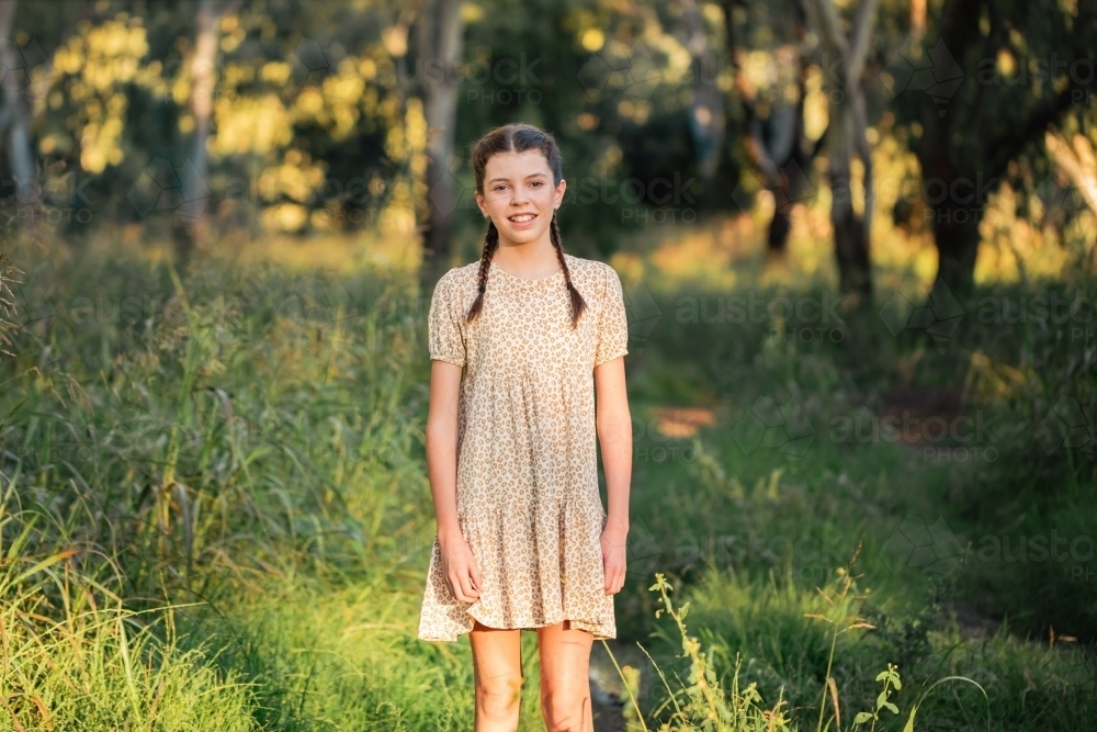 Portrait of happy pre-teen girl wearing dress in Australian country bush setting - Australian Stock Image